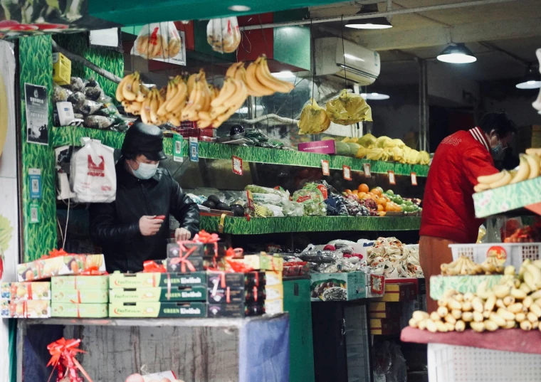 people wearing masks in the produce section of a grocery store