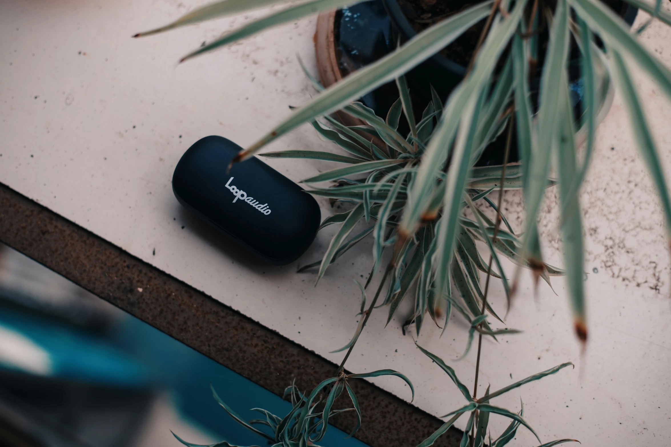 a bluetooth headphone lying on top of some plants