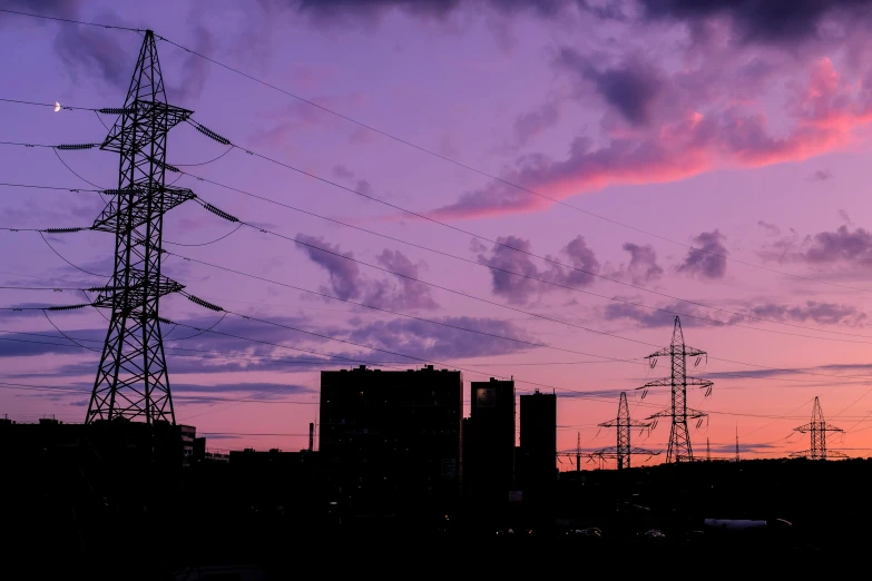 the sun is setting over an electric line in the city