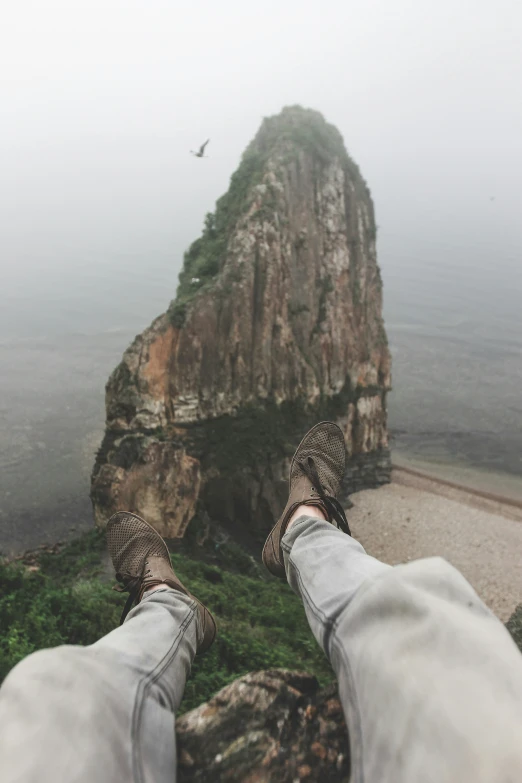 a person's feet propped up by an overlook point with mountain and a sea