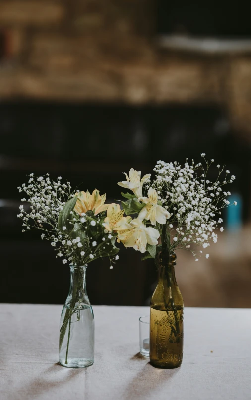 two glass bottles with flowers in them on a table