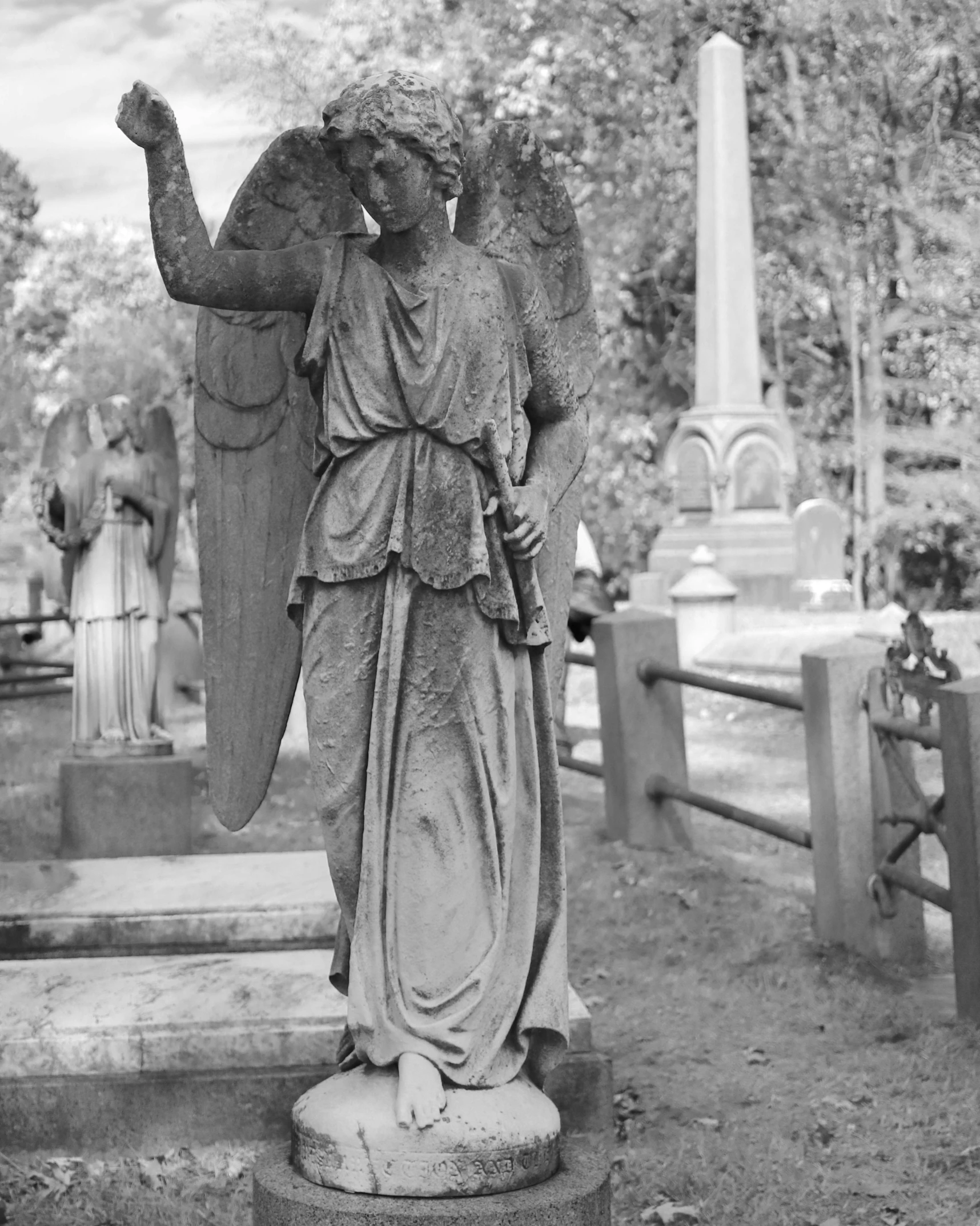 an angel statue standing in a cemetery looking toward the cross