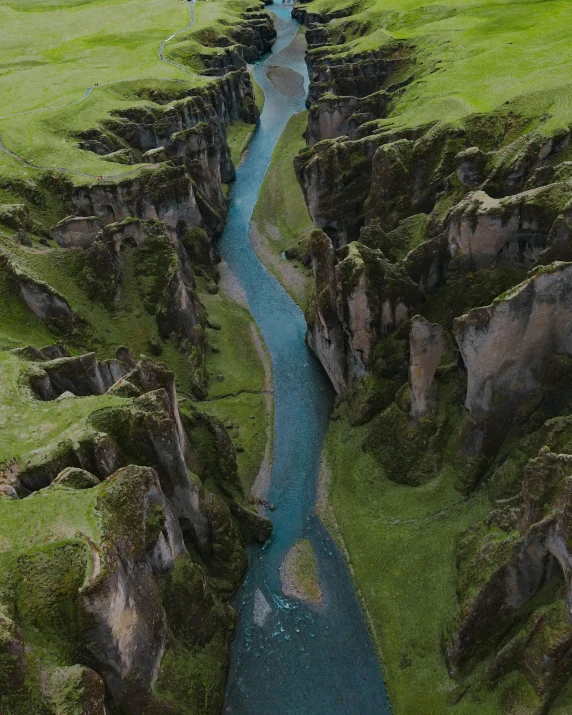 a blue river running through the side of a grassy field