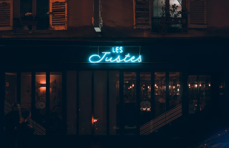 a large neon sign above a bar that says les jouettes