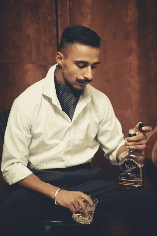 a man sitting down holding a glass of alcohol