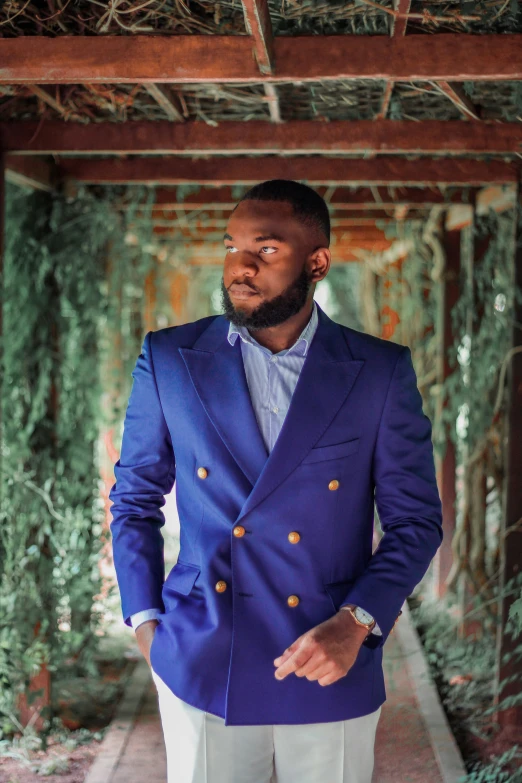 a young man wearing a blue jacket and white slacks