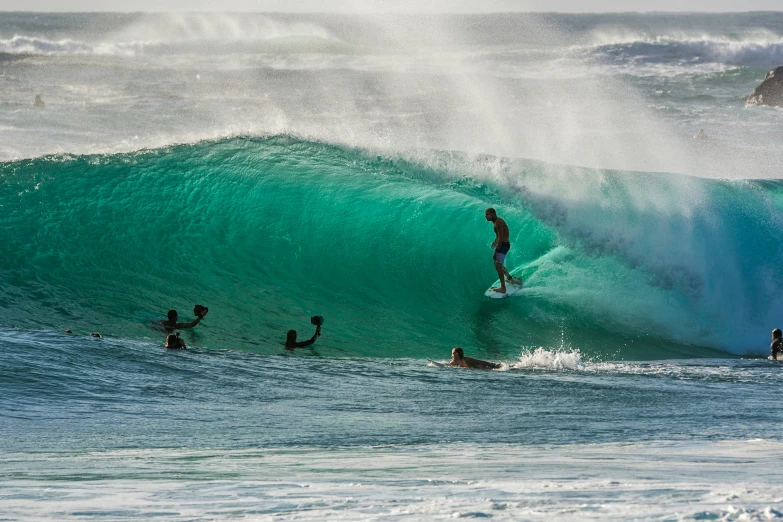a group of surfers riding the crest of a wave
