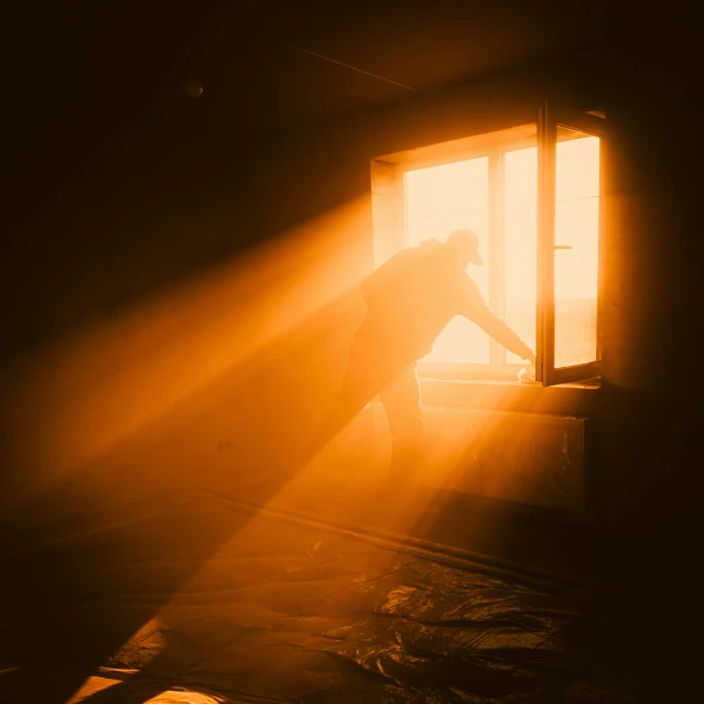 a person looking out of a window at the sunlight