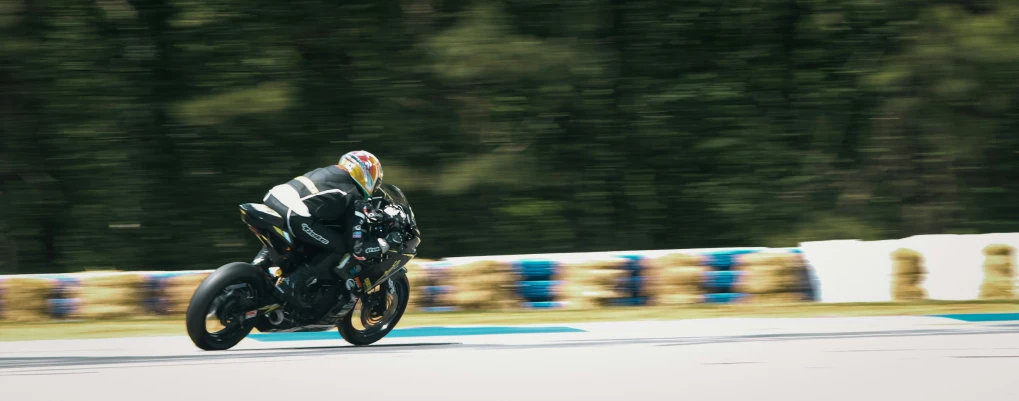 person racing black motorcycle on a track in the middle of forest