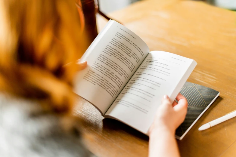 woman reading a book on a wooden table