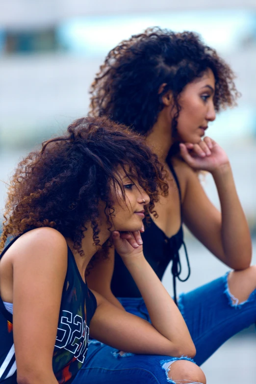 two women wearing black top and jeans sitting together