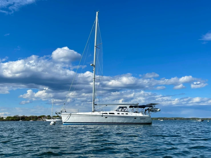 a sailboat traveling on the water under a blue cloudy sky