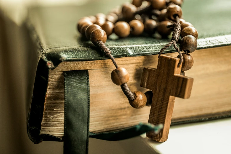 a rosary hanging from a green leather book