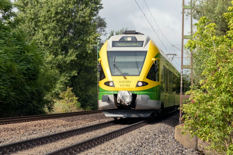 an electric train riding along the tracks near some trees