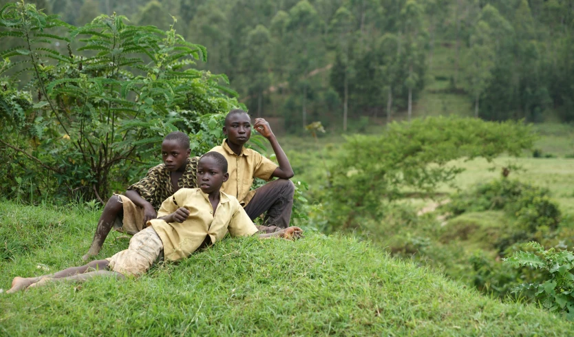 four people sitting on top of a lush green hillside