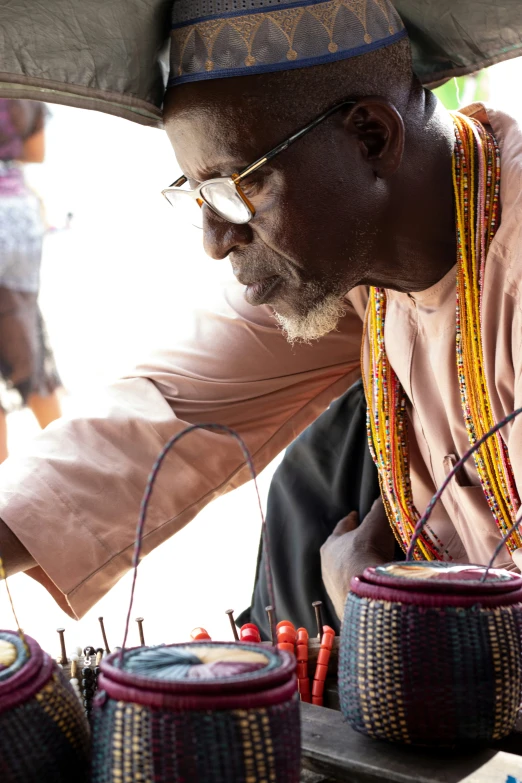 an old man wearing a colorful hat and carrying some baskets