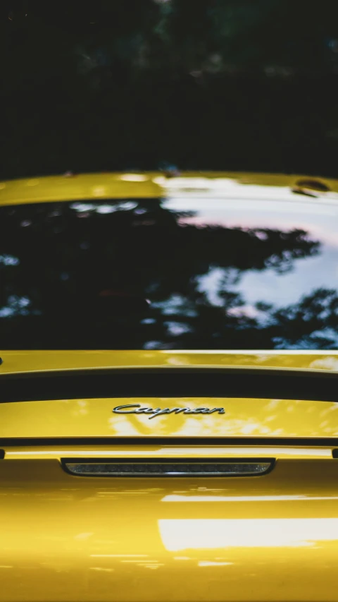 a bright yellow car with trees in the background