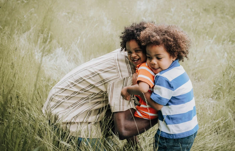 a little girl is kissing a man's chest in the tall grass