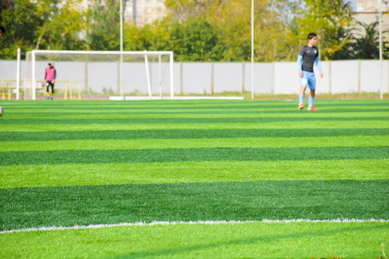 two young men walking in the grass around soccer equipment