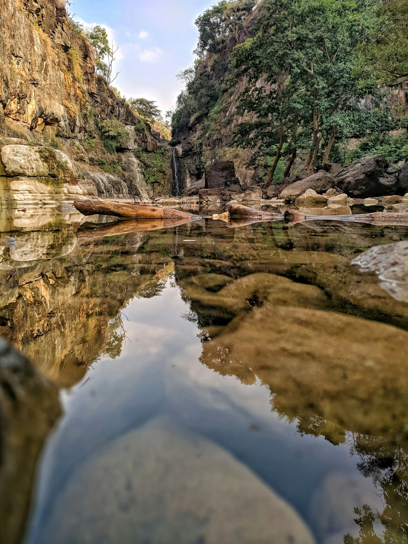 a body of water in a rocky area with rocks on the side and trees to the right