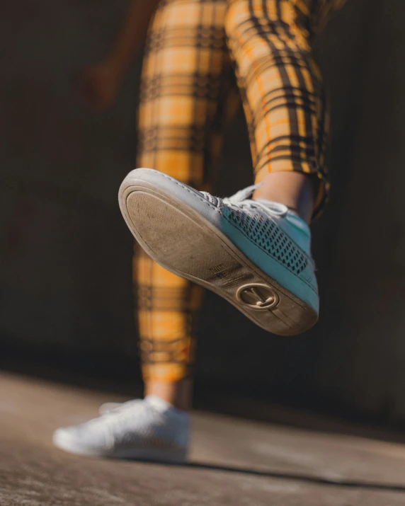 a person with blue shoes standing by a wall