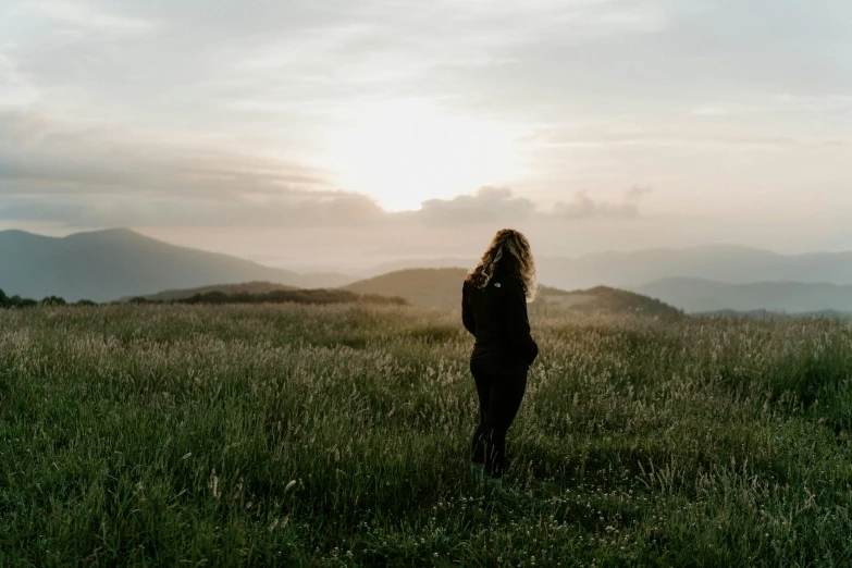 a woman stands alone in an open field