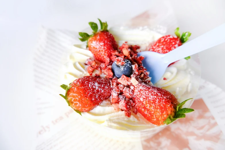 a spoon in a small dessert that has berries on top