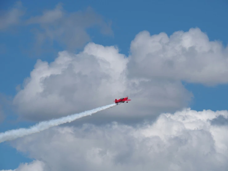 a red plane with smoke leaving behind the tail