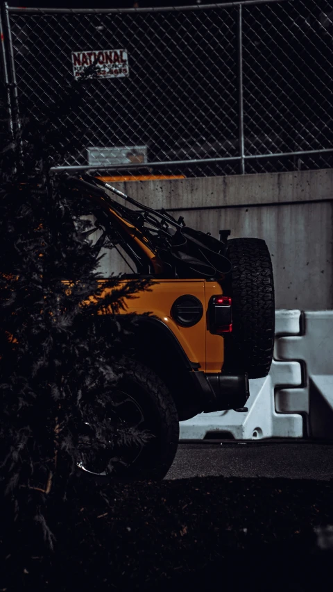 an orange jeep parked in a parking lot at night