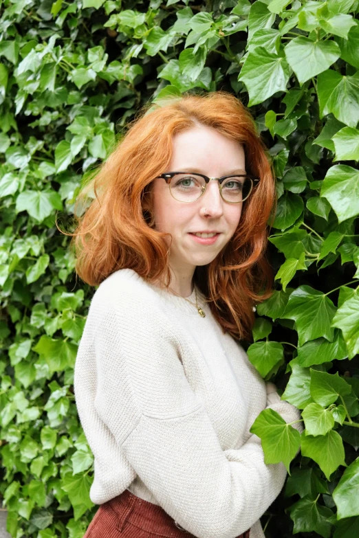 a young red headed girl wearing glasses posing for the camera