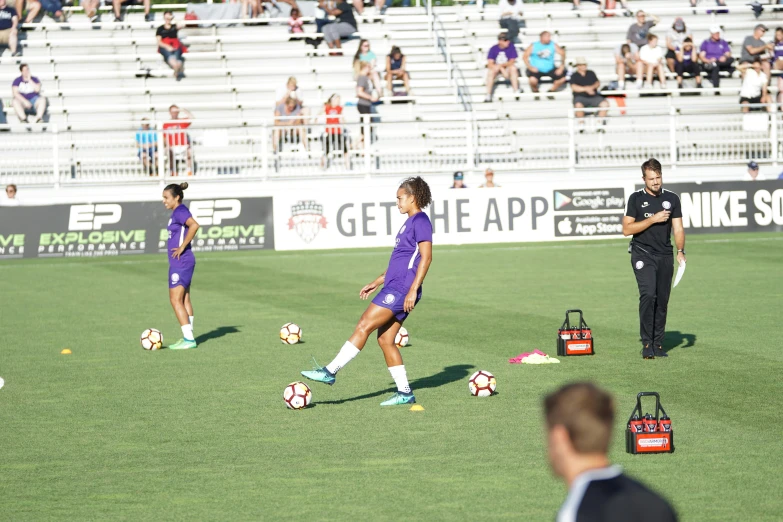 a group of girls kicking around soccer balls on a field