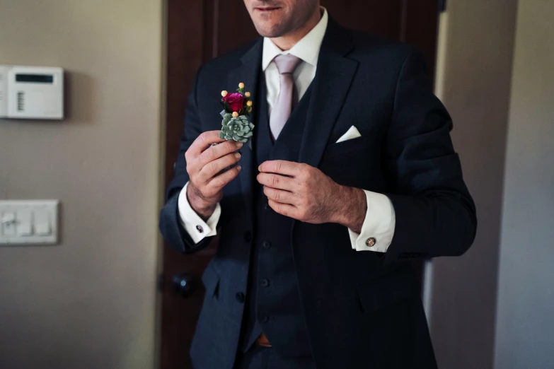 a man in a suit putting on a flower