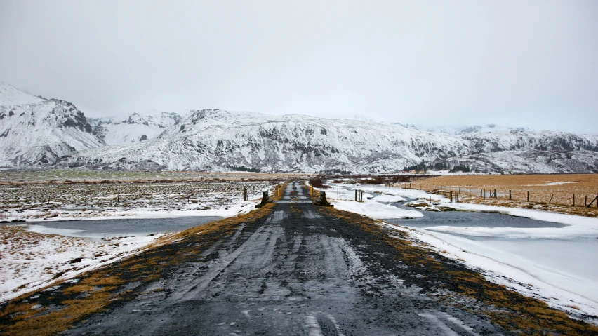 a long road with snow covered mountains in the distance