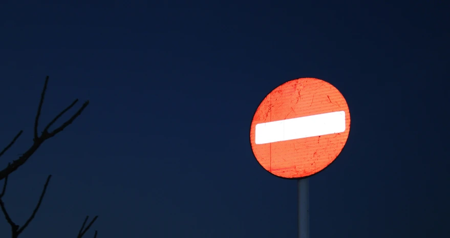 a traffic sign sitting next to a barren tree