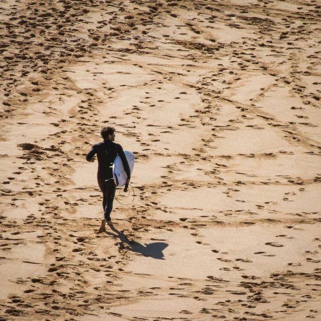 there is a man walking with a surfboard on the beach