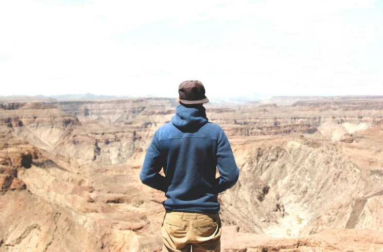 a man standing in front of a canyon overlooking the vast mountains