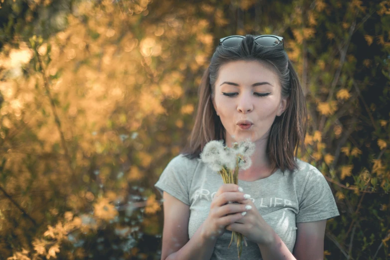 a girl holding a flower blowing bubbles in the wind