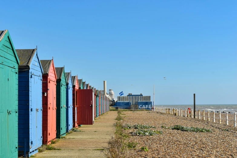 rows of beach huts line the beach with the ocean in the background