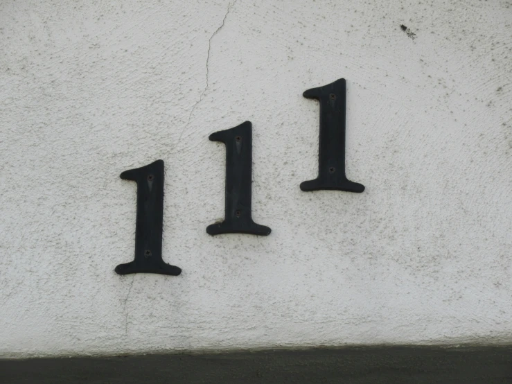 the letters 11, 11, and 11 are carved into a white stucco wall