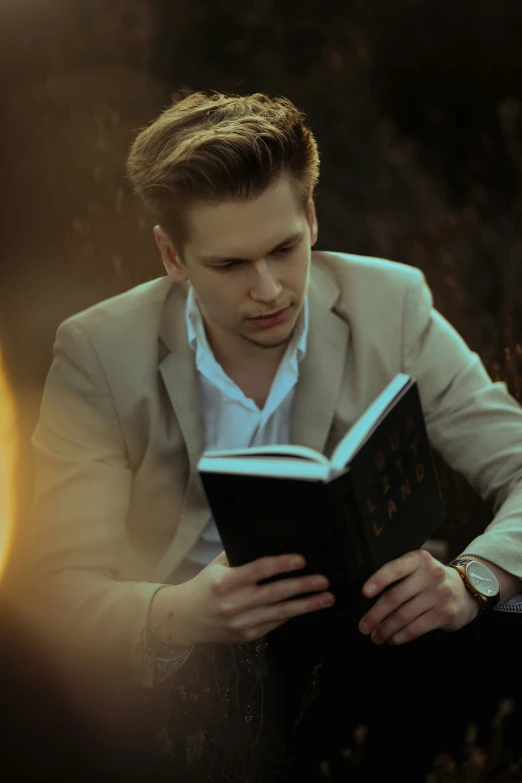 a man reading a book while sitting on a bench