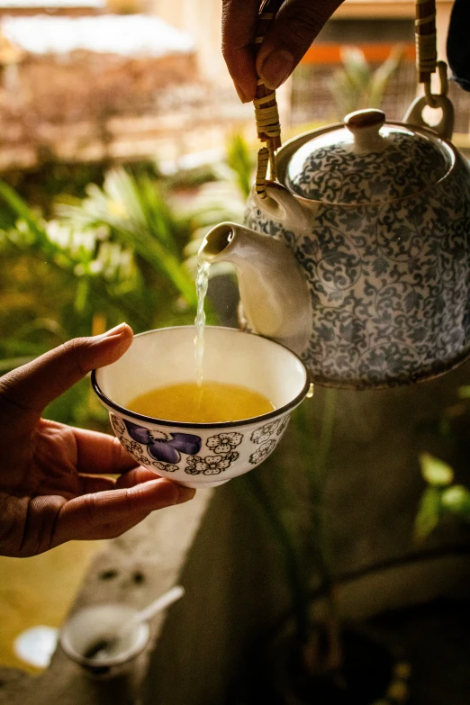 a woman pouring tea from a kettle into a cup