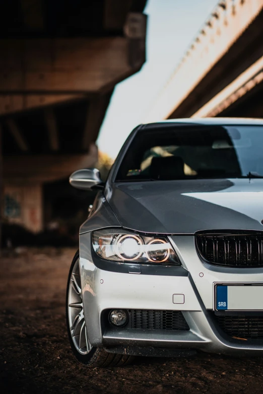 a grey car parked near a bridge on a cloudy day