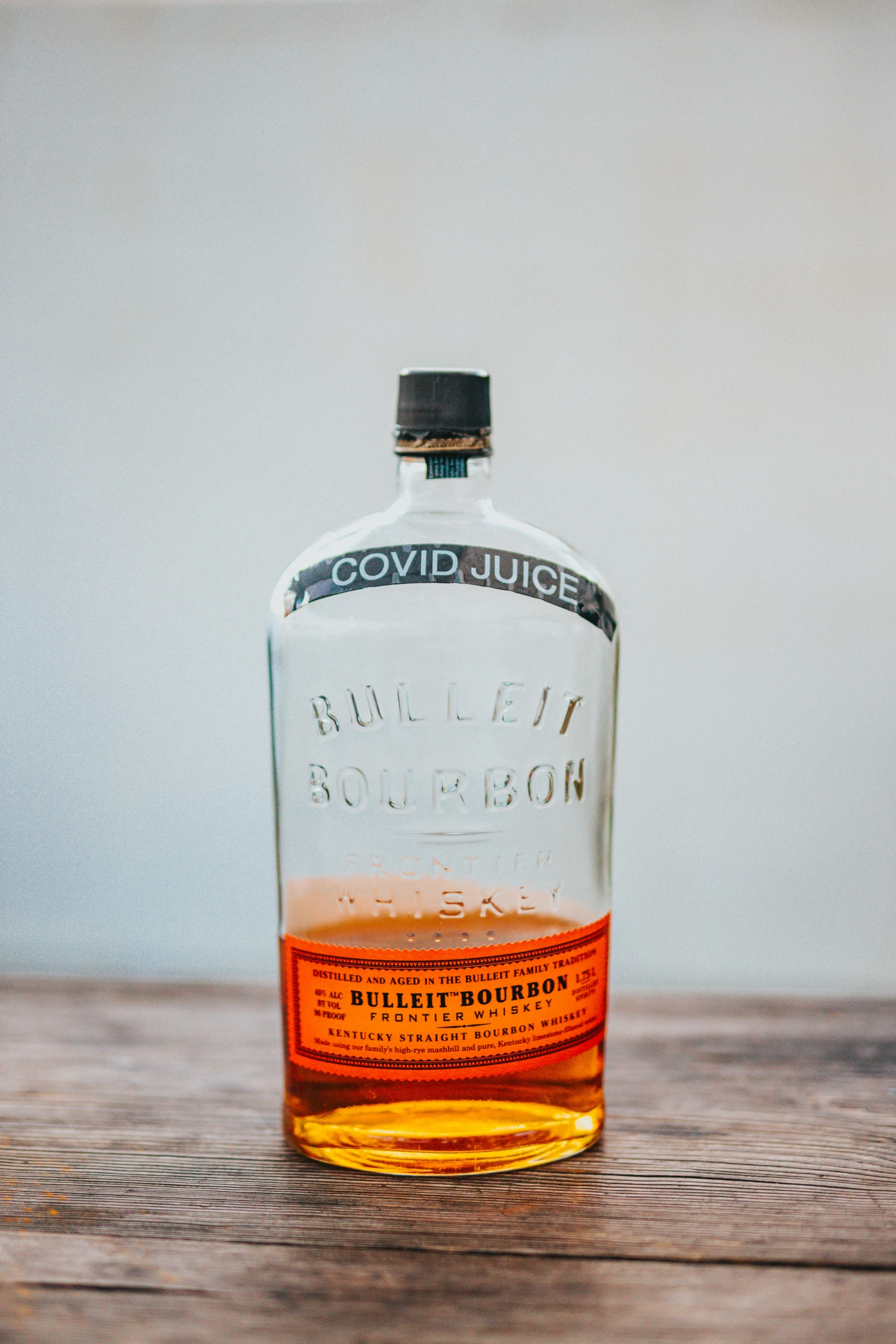 a liquor bottle with orange liquid sitting on a table