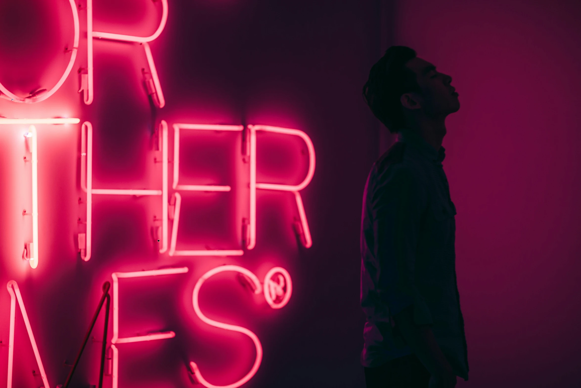 a man looking up at the light in the neon sign