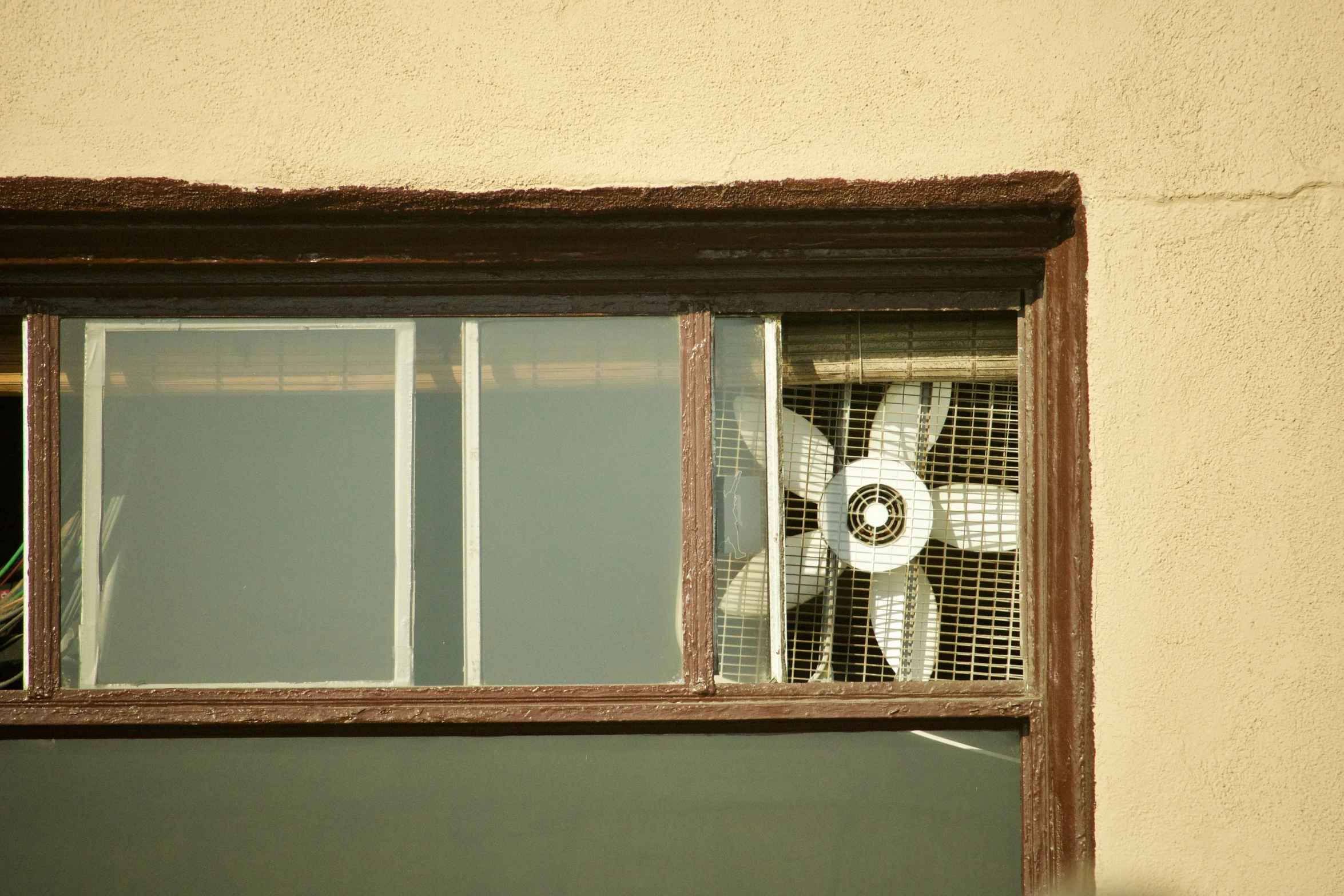 a wall with a fan in the window