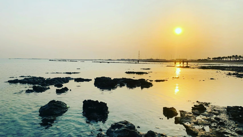 a view of the ocean with rocks at sunset