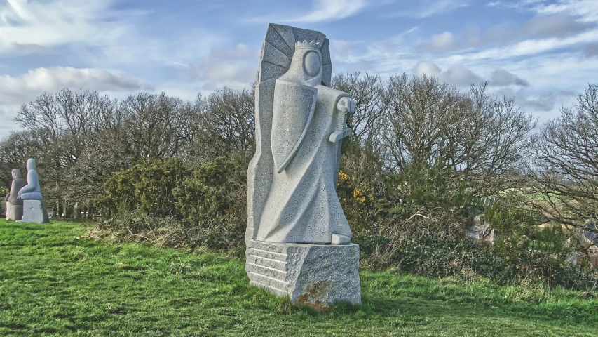 a white statue in a grassy field under a blue sky