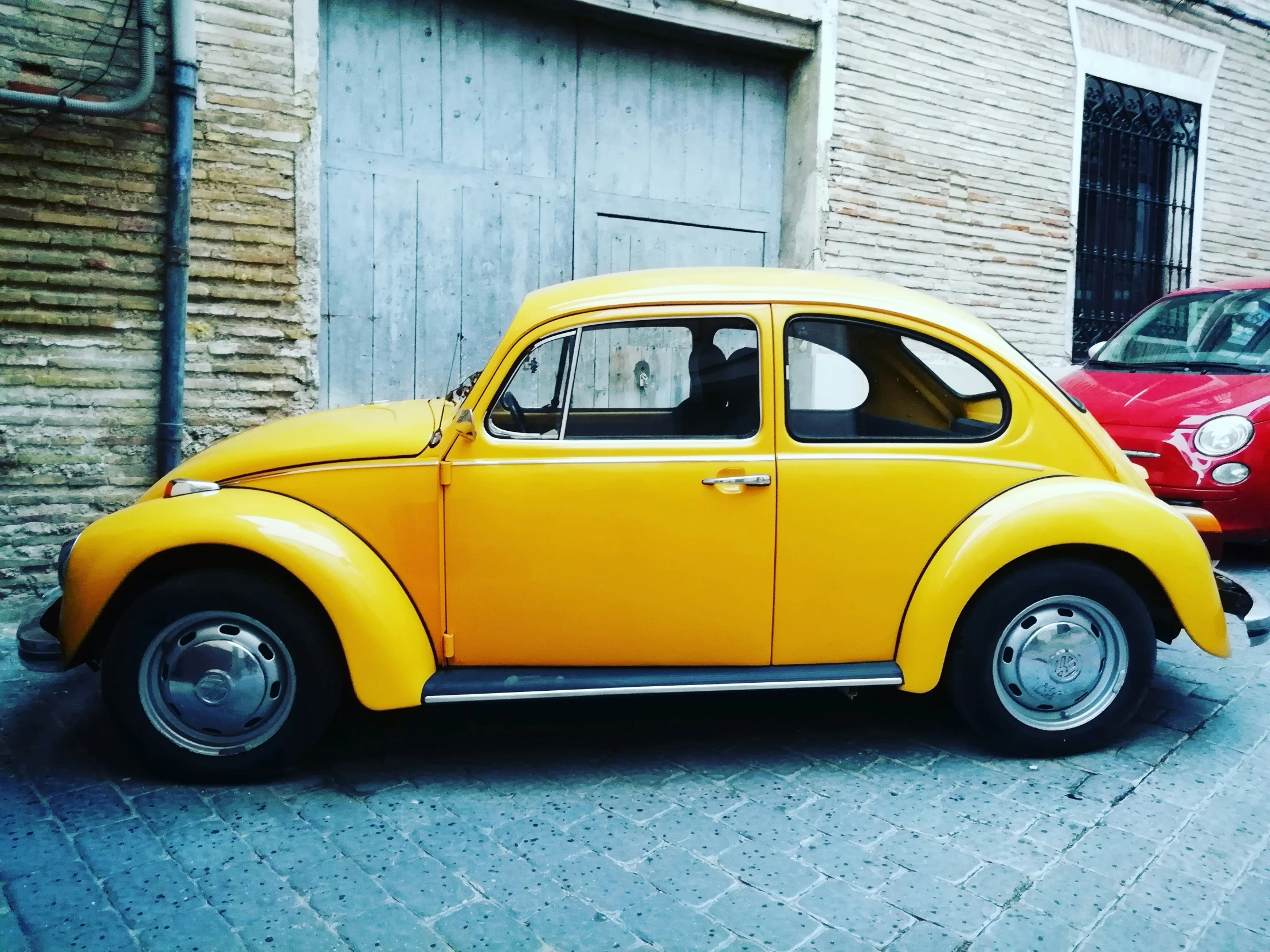 a bright yellow vw beetle sitting in front of a brick building