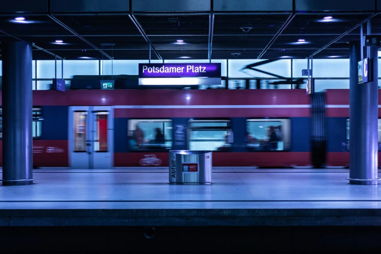 a train going by a red building with people passing