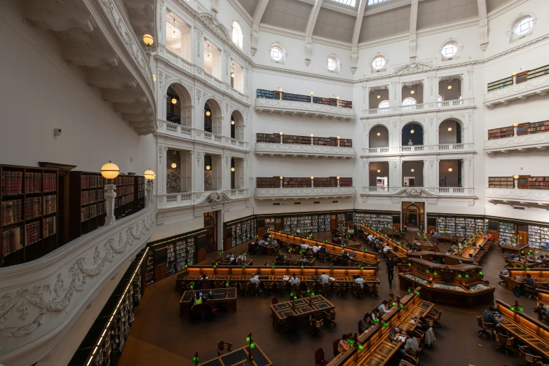 a liry filled with people sitting at long tables and a giant ceiling